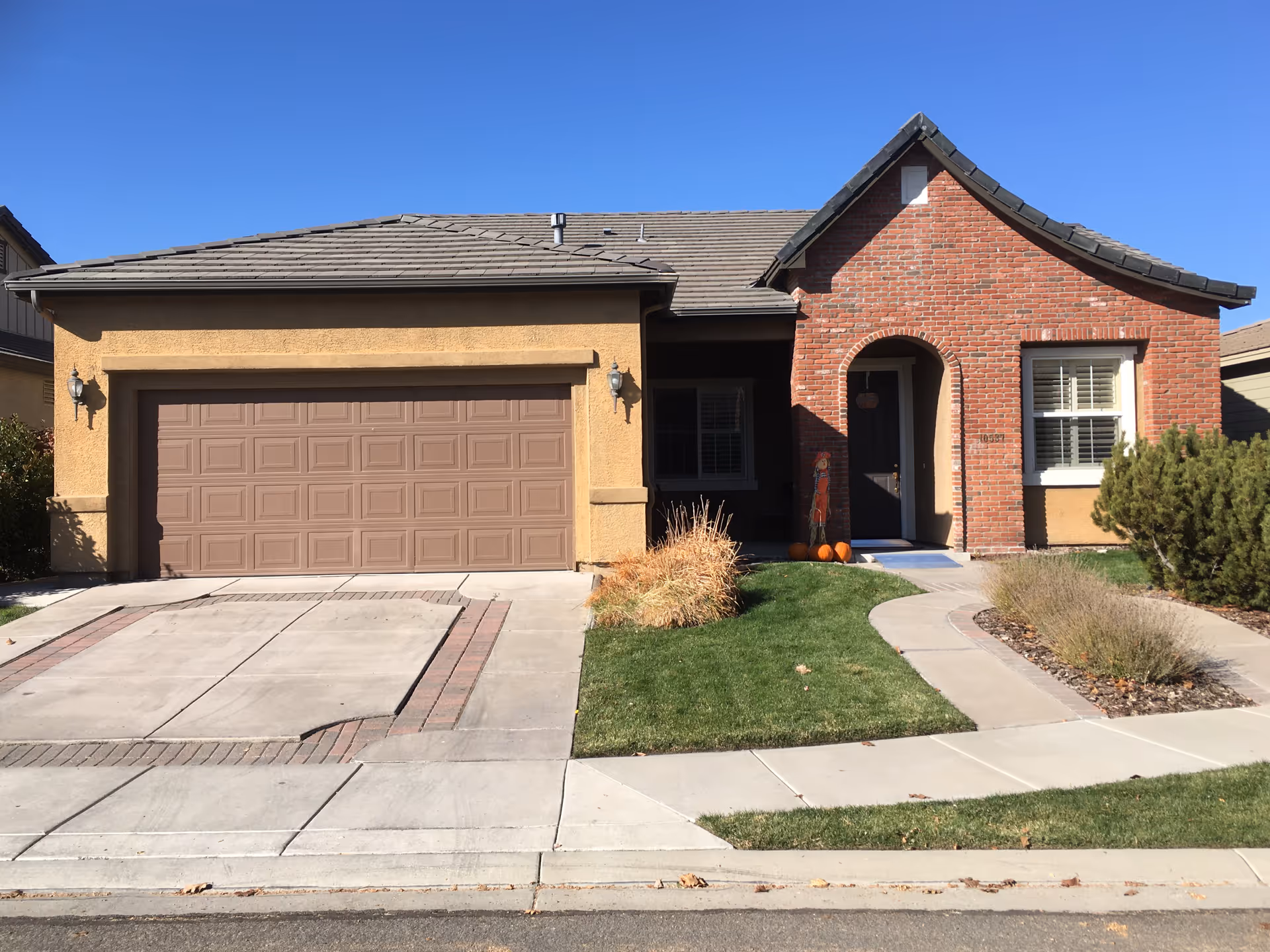 Front view of a single-story house with a two-car garage and arched entry.