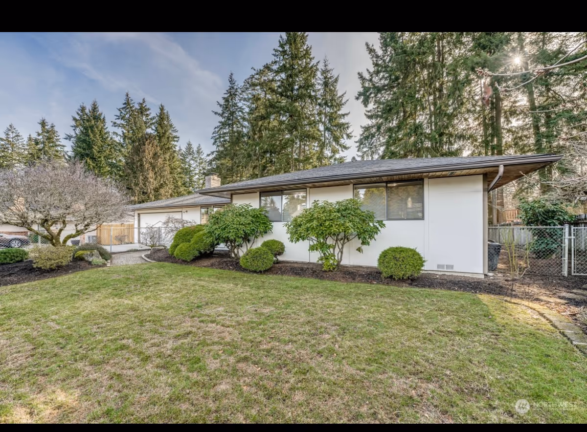 Exterior view of a single-story adult family home with a manicured yard and tall trees.