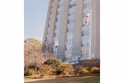Tall multi-story building with a flag and landscaped entrance in front.