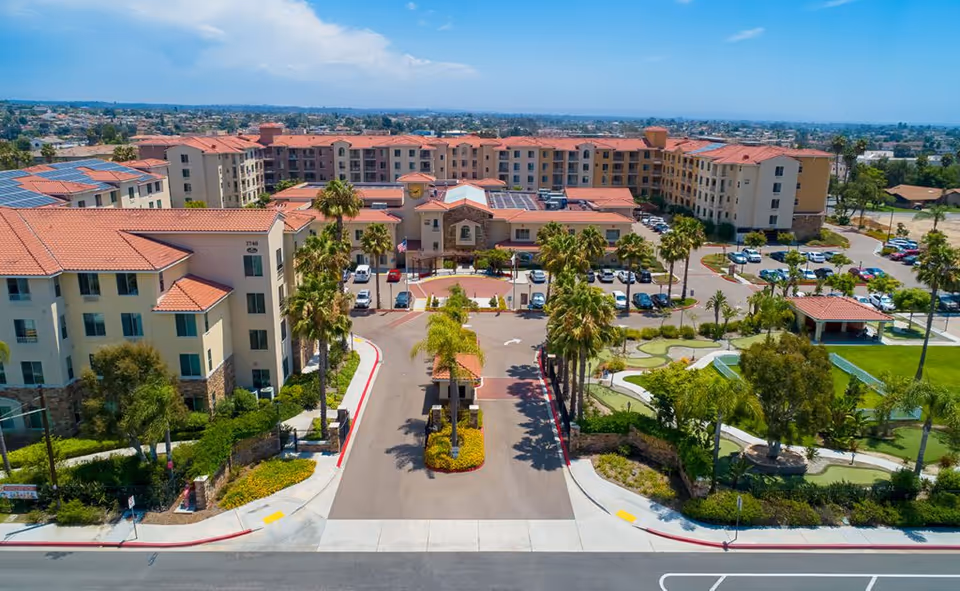 Aerial view of Paradise Village senior living campus, tan buildings and palm trees.