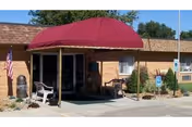 Front entrance of Sterling County Nursing Home with red canopy, benches, flag, and accessible signage.