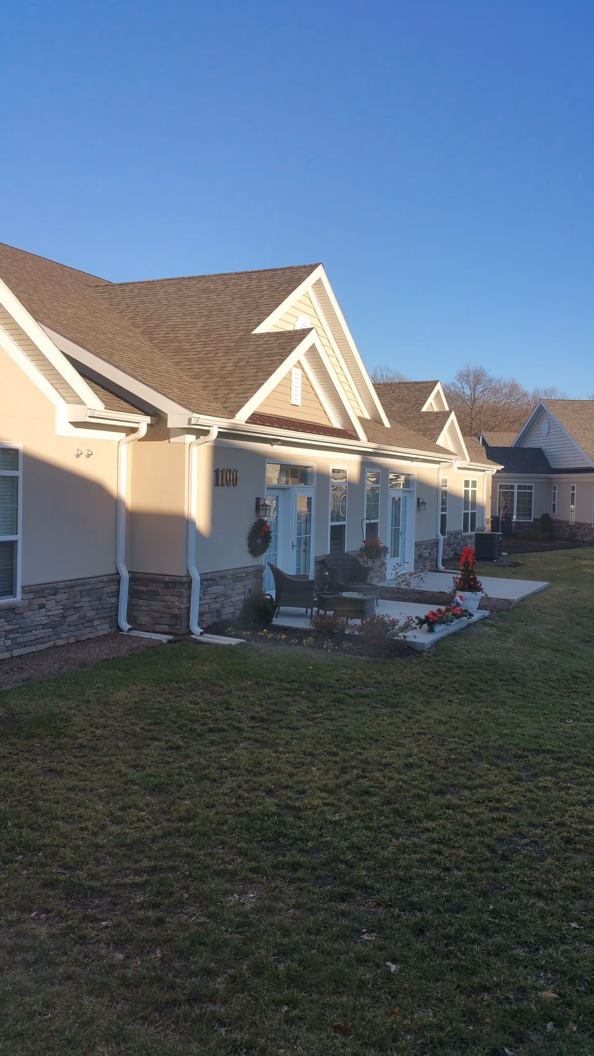 Exterior view of Holland Village Senior Living with beige buildings, porches, and manicured lawn