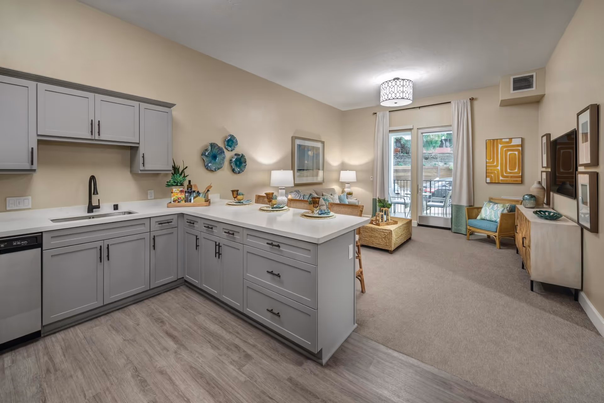 Modern gray kitchen with an island opens to a living area and glass patio doors.