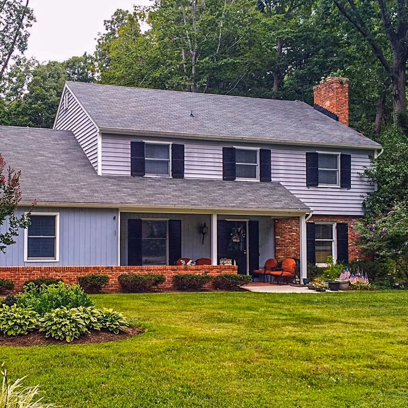 Two-story suburban-style senior living building with a covered front porch and manicured lawn.