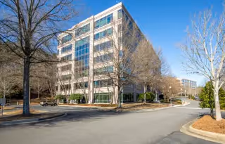 Exterior view of a multi-story senior living facility with glass façade and trees.