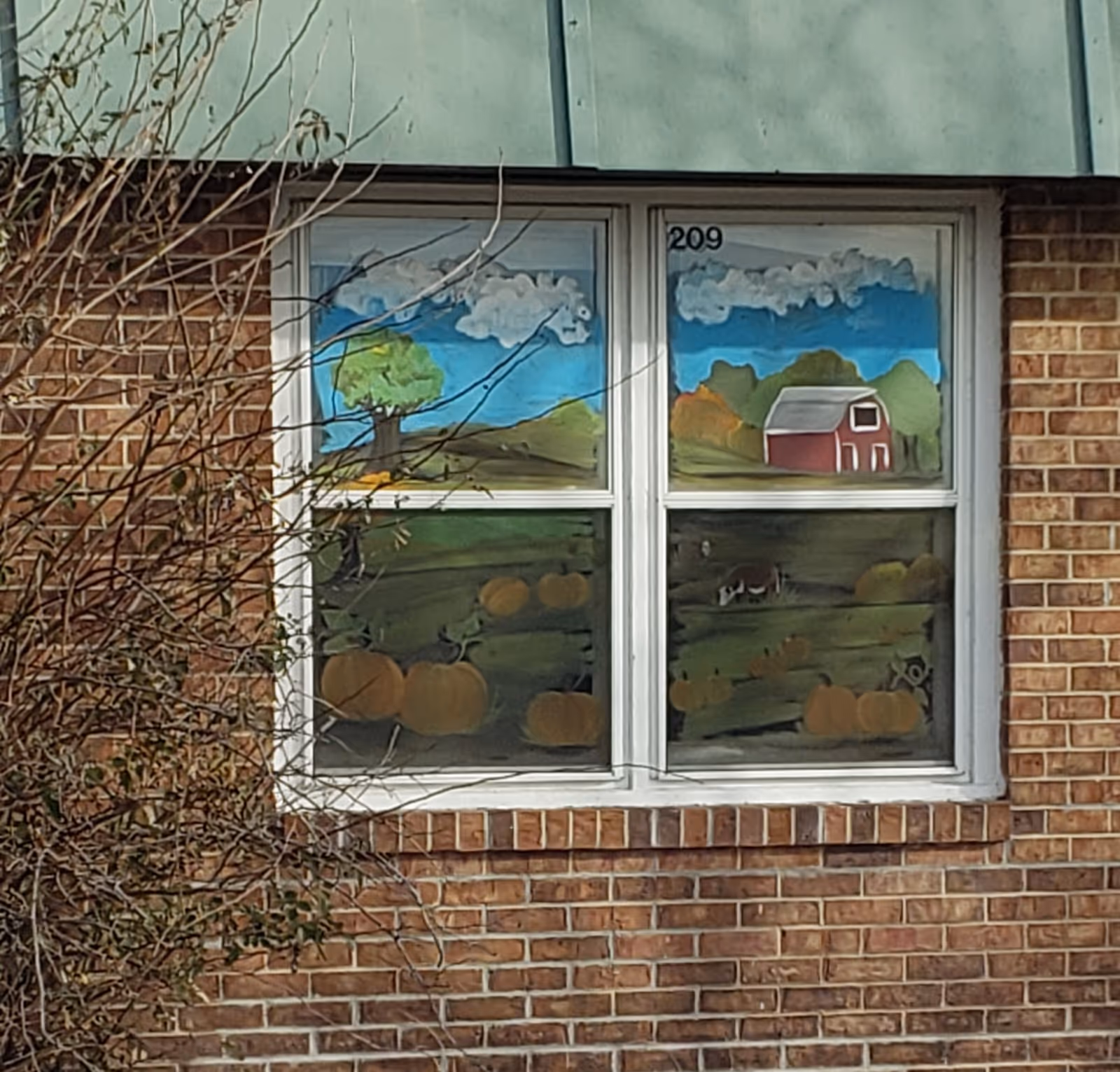 Exterior brick wall of nursing home with a window mural of countryside pumpkins.