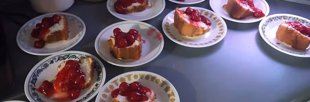 Several small plates each with a slice of cherry-topped cheesecake arranged on a table.