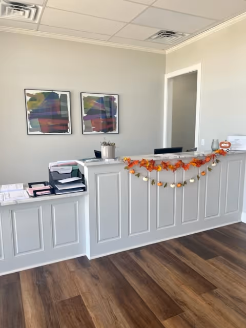 Reception desk in a bright lobby with autumn garland and framed artwork.