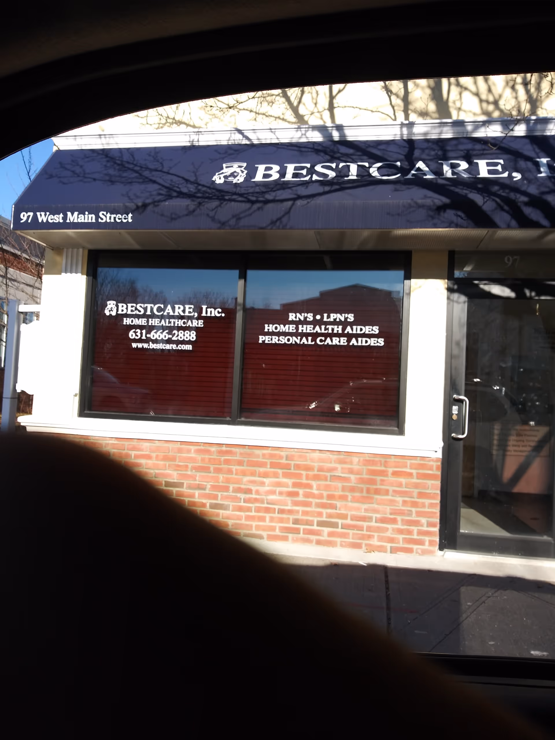 Exterior view of BestCare, Inc. storefront with blue awning and brick facade.