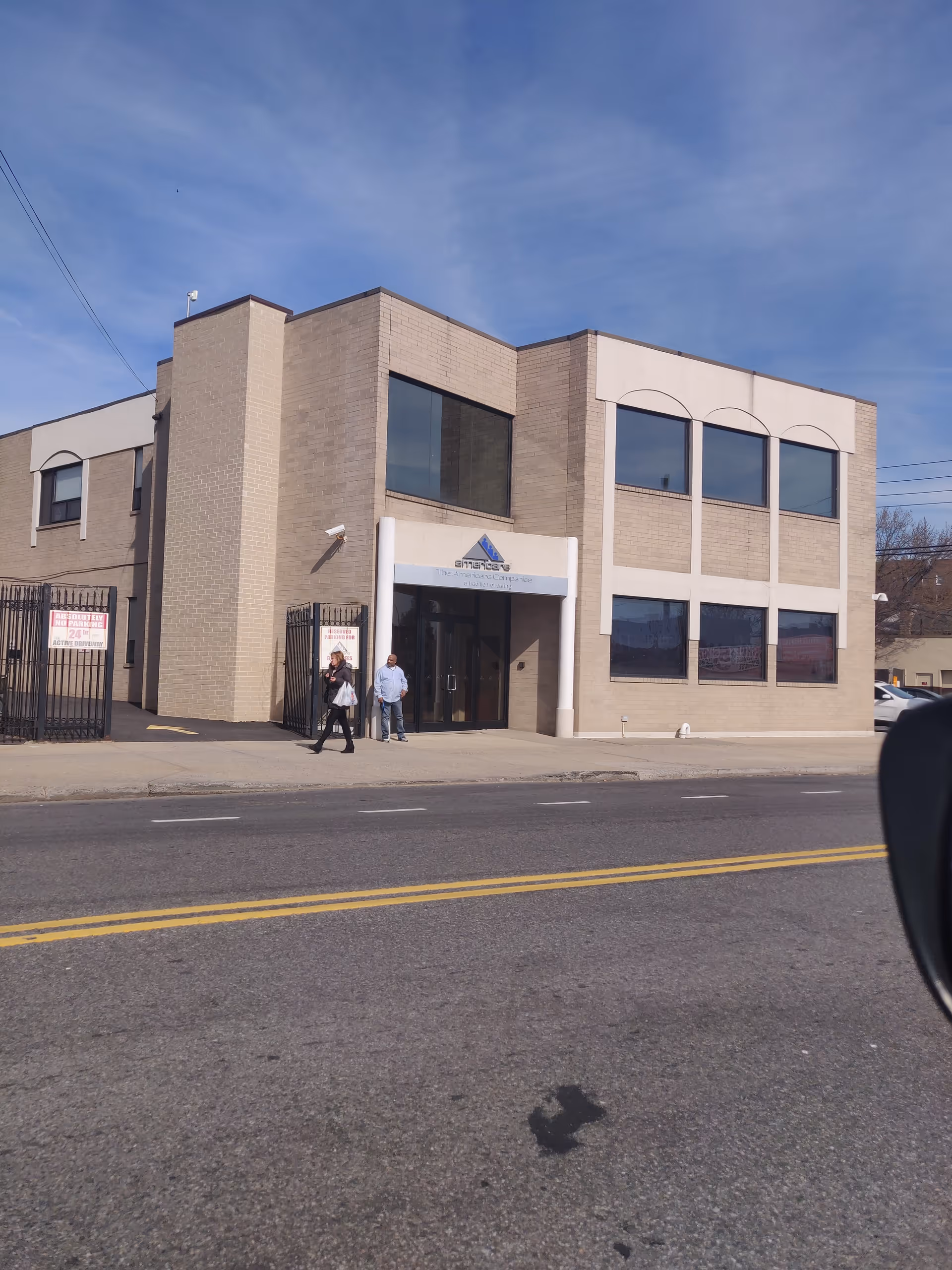 Exterior view of Americare Brooklyn building with entrance and two people on sidewalk