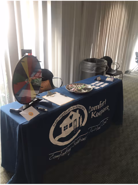 Blue-covered table with a colorful spinning wheel and brochures in a sunlit interior.