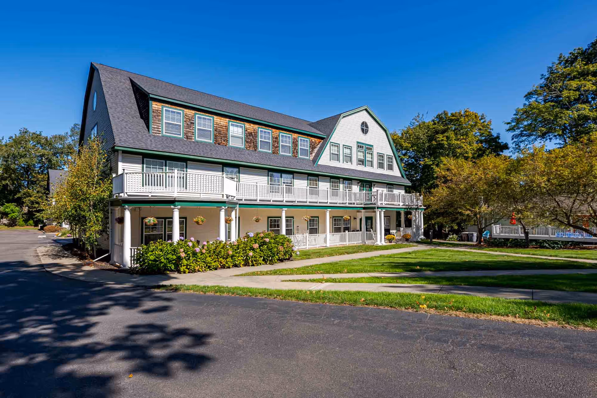 A large, two-story senior living building with white railings and a manicured lawn.