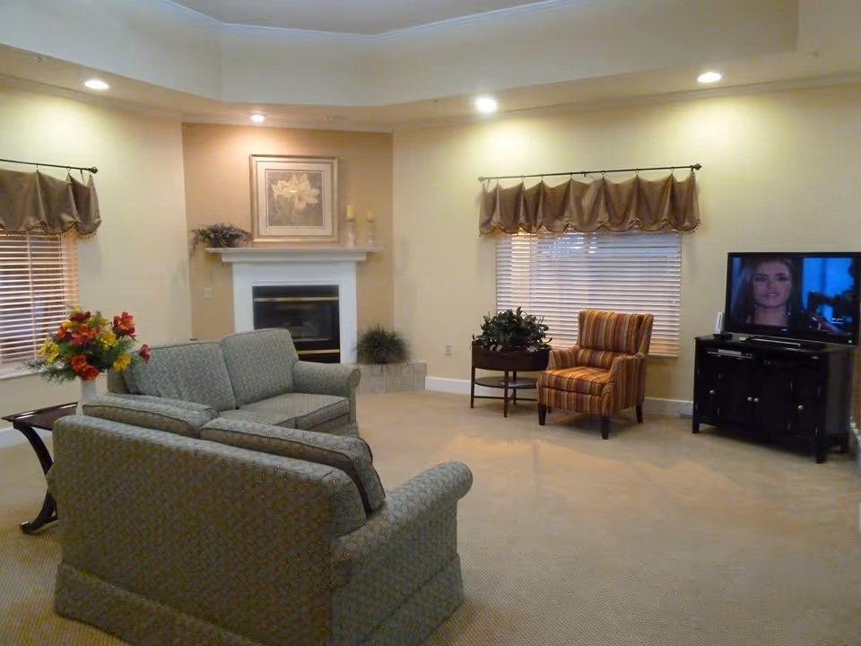 Spacious living room with sofas arranged around a fireplace, a striped armchair, TV on a stand and decorative accents.