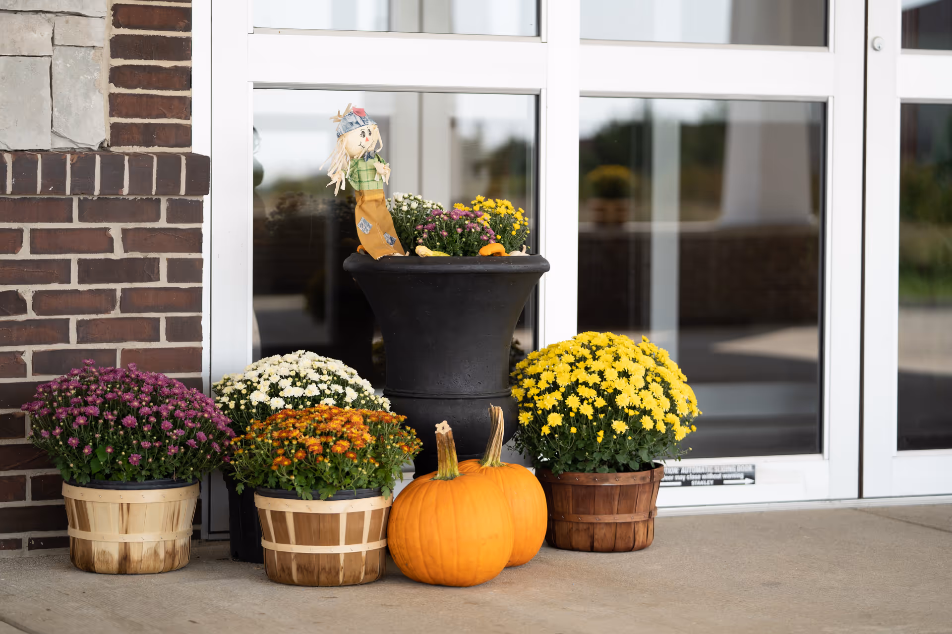 Front entrance of Gibson City Villas of Holly Brook with potted mums and pumpkins.