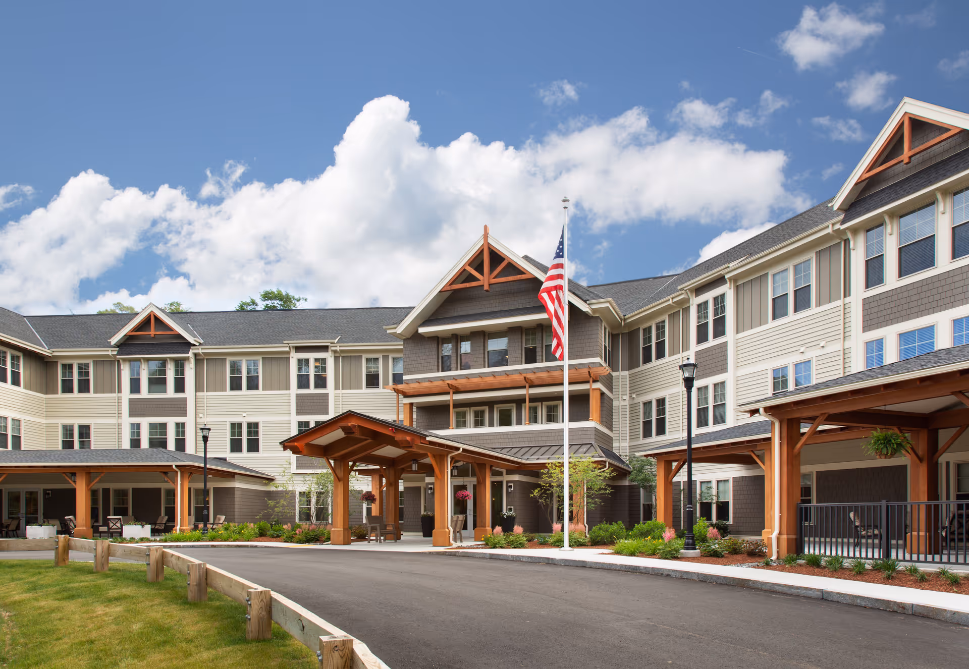Exterior view of a multi-story senior living facility with an American flag and covered entrance.