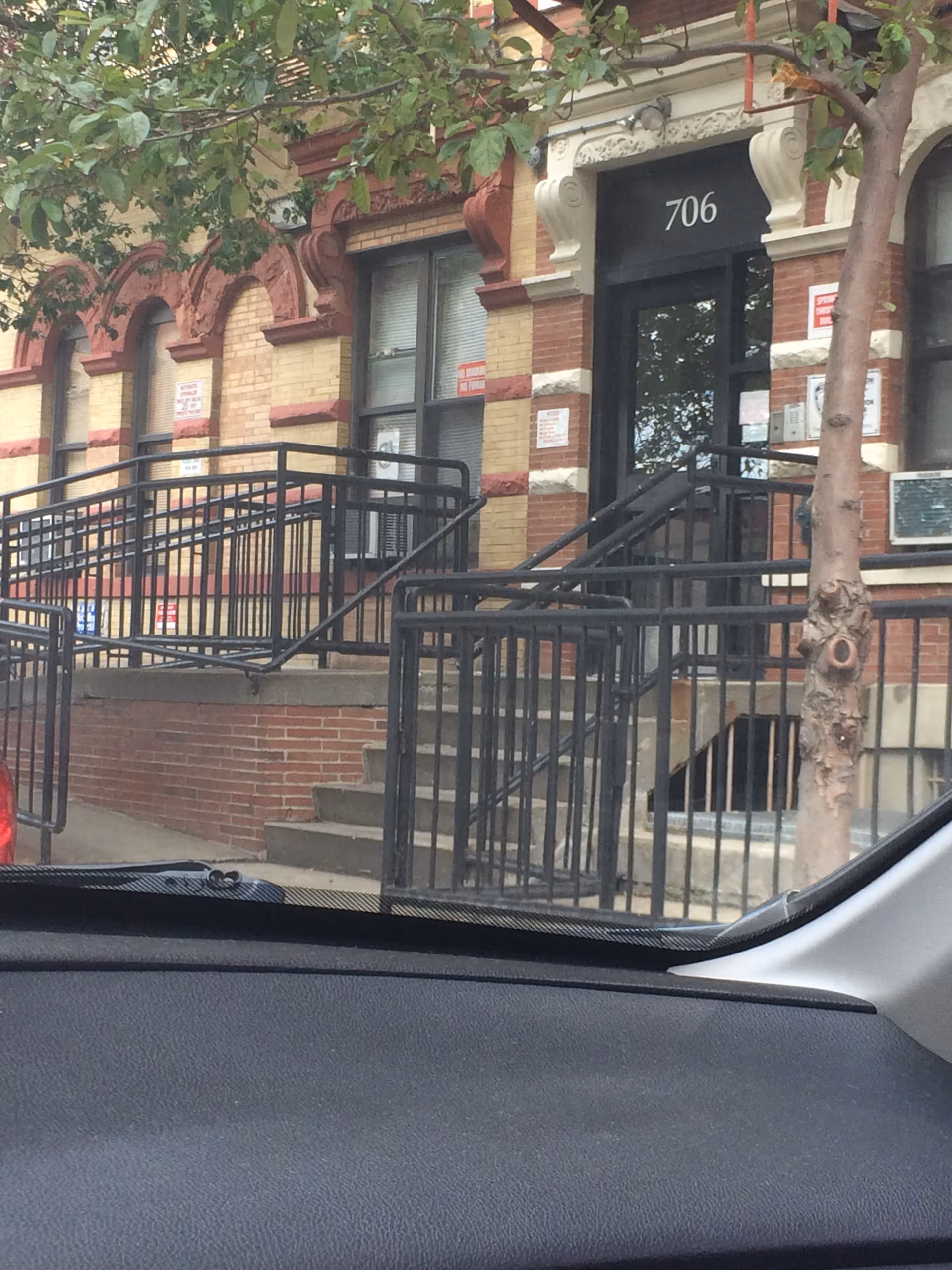 Brick building entrance with stairs and black metal railings labeled 706.
