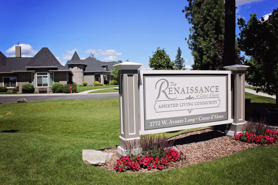 Entrance sign for The Renaissance assisted living community on a manicured lawn with the facility buildings visible behind it.