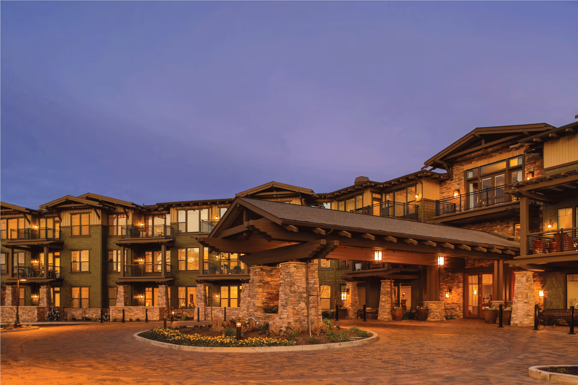 Exterior view of Fountaingrove Lodge with a stone entrance canopy and balconies at dusk.