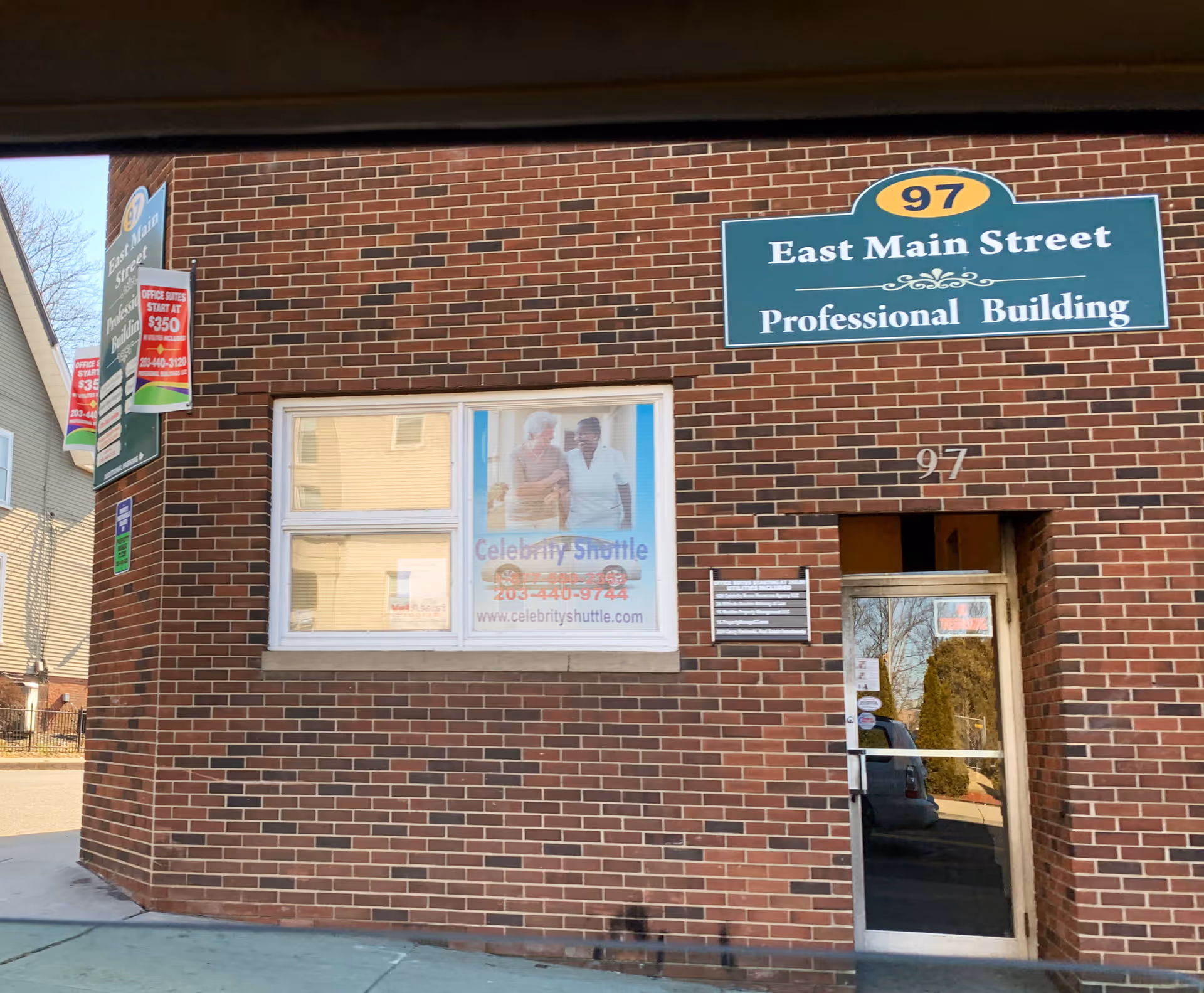 Brick building with a green sign reading East Main Street Professional Building and a window poster.