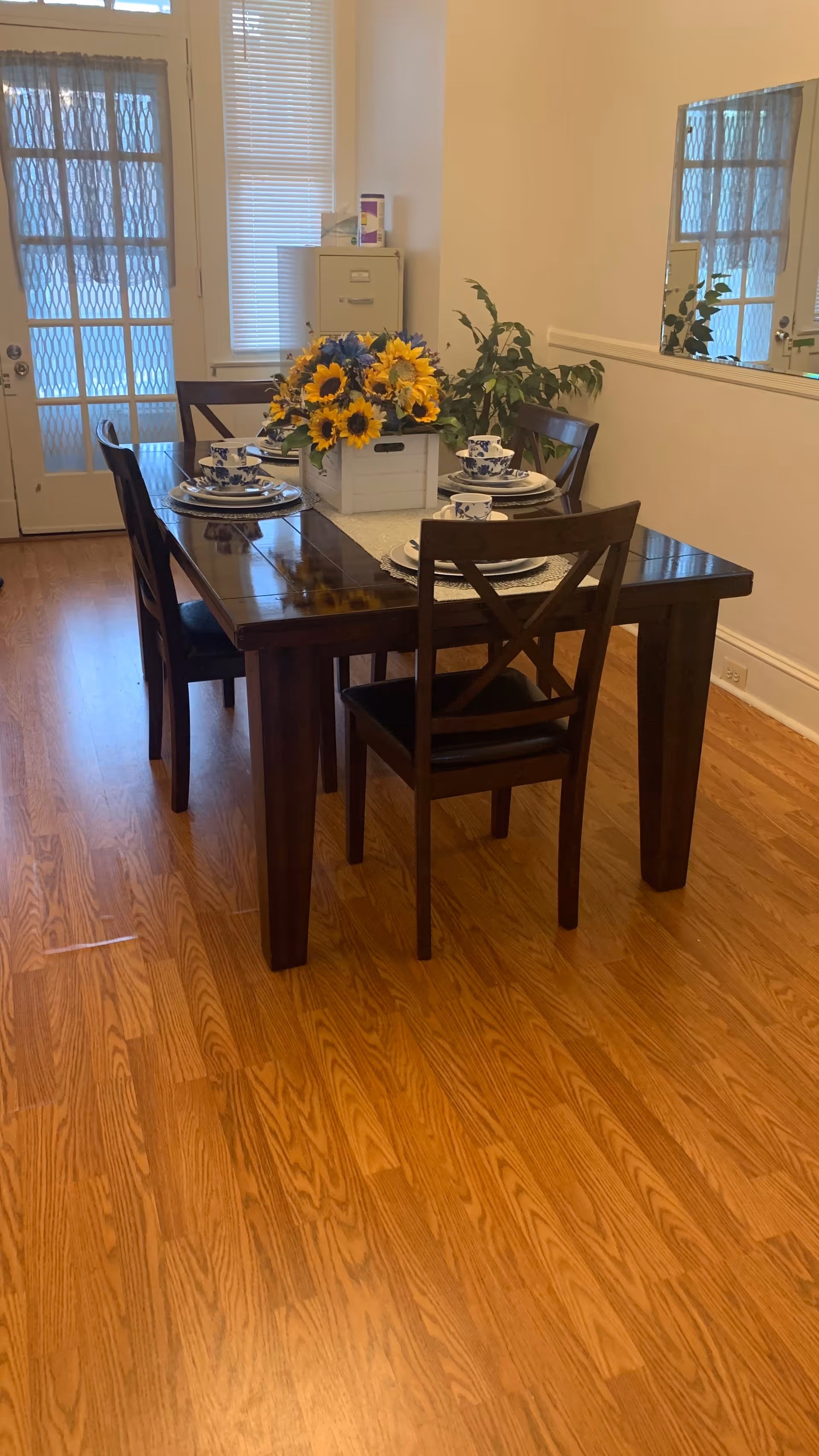 Dining room with wooden table set for four and sunflower centerpiece.