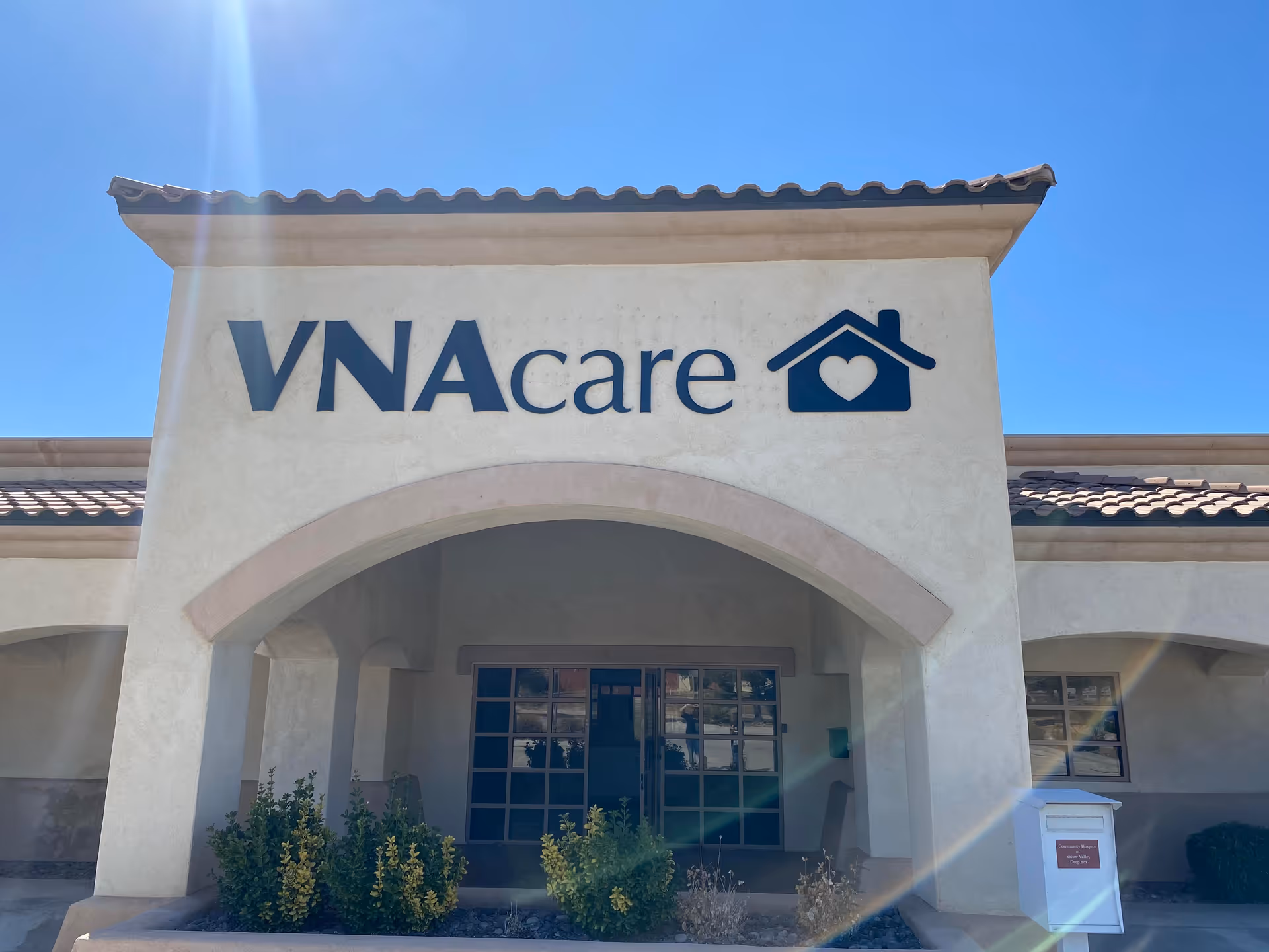 Front view of a VNAcare facility featuring an arched entrance and blue sky.