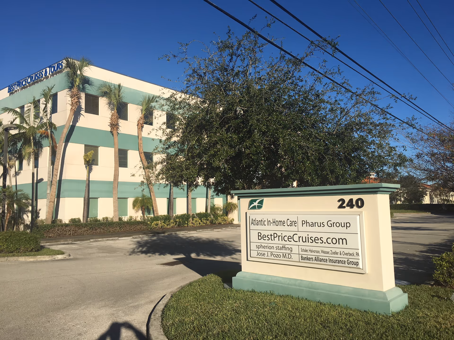 Exterior view of a cream building with teal stripes and a front sign.