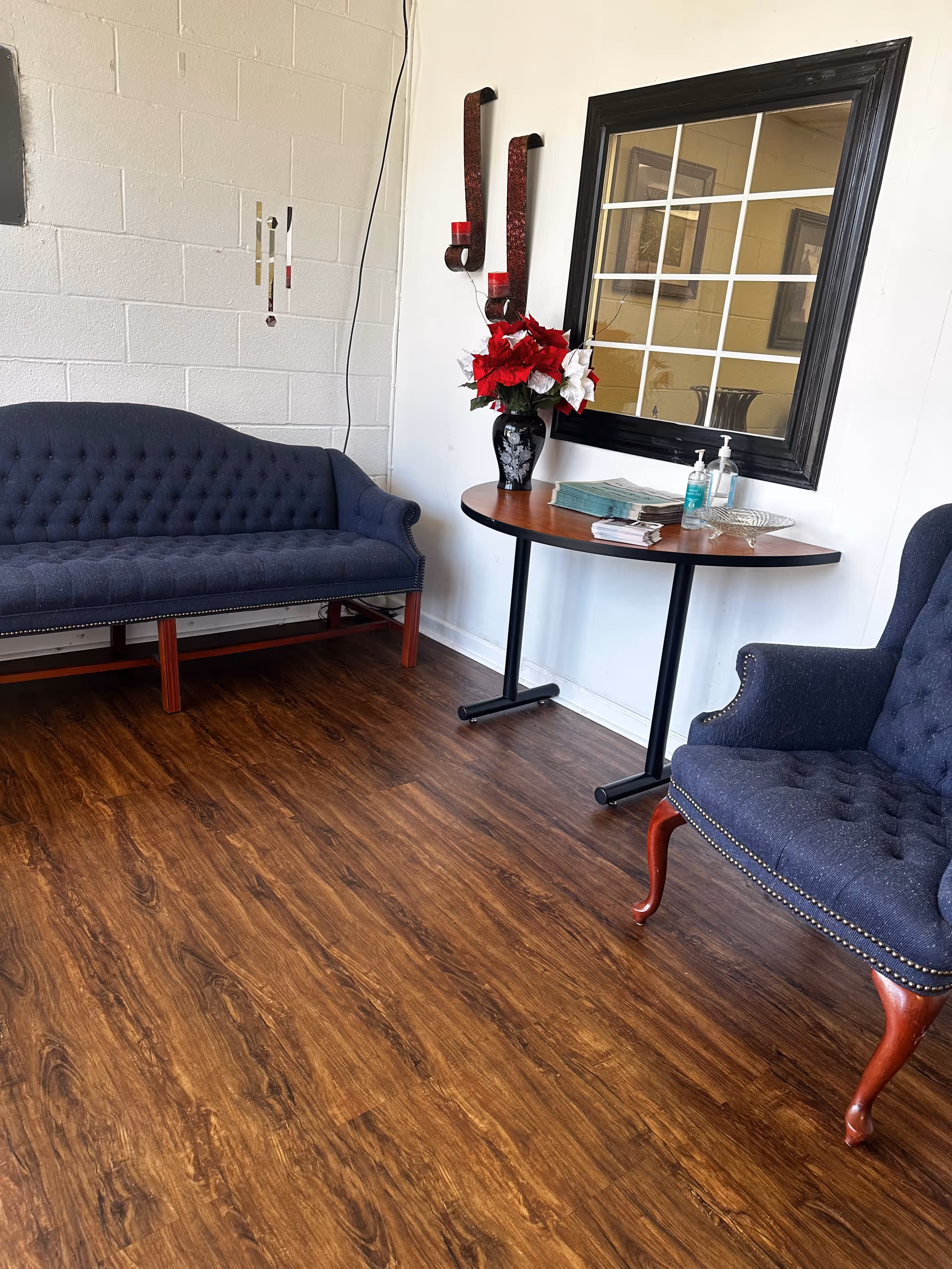 A cozy senior living lounge with blue tufted couches, a round table, and decor.