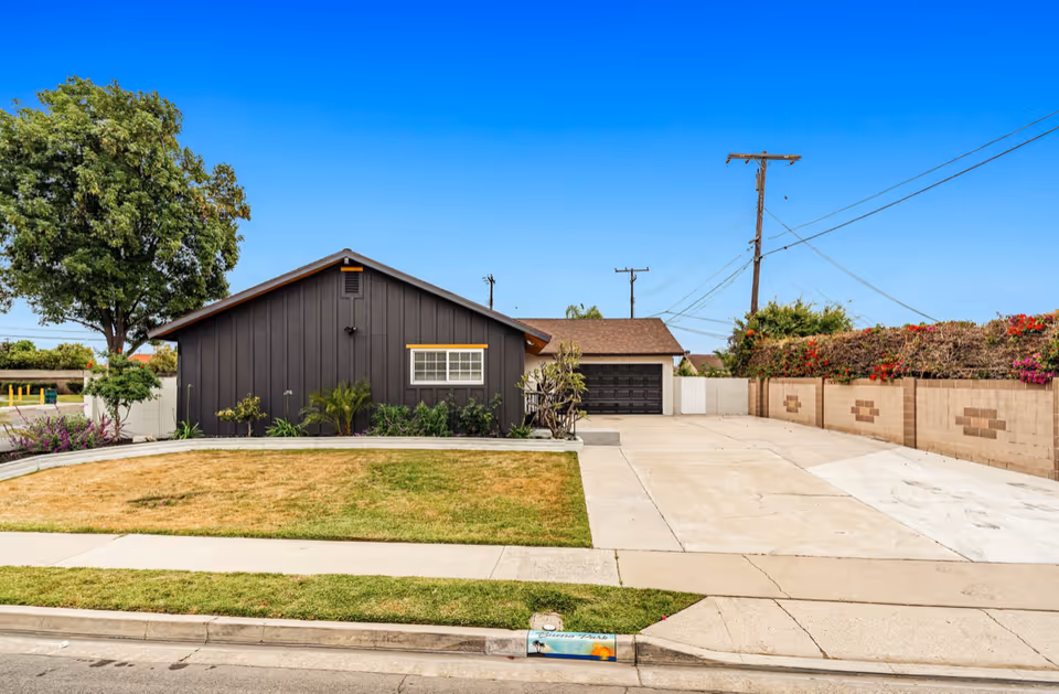 A single-story dark exterior building with a long driveway and front yard.