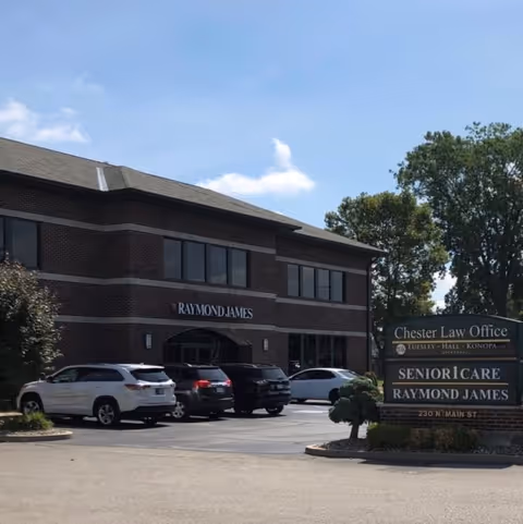Exterior view of a brick office building with Senior1Care signage and parked cars.