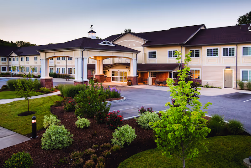 Exterior view of an assisted living facility with a covered entrance and landscaped front yard.