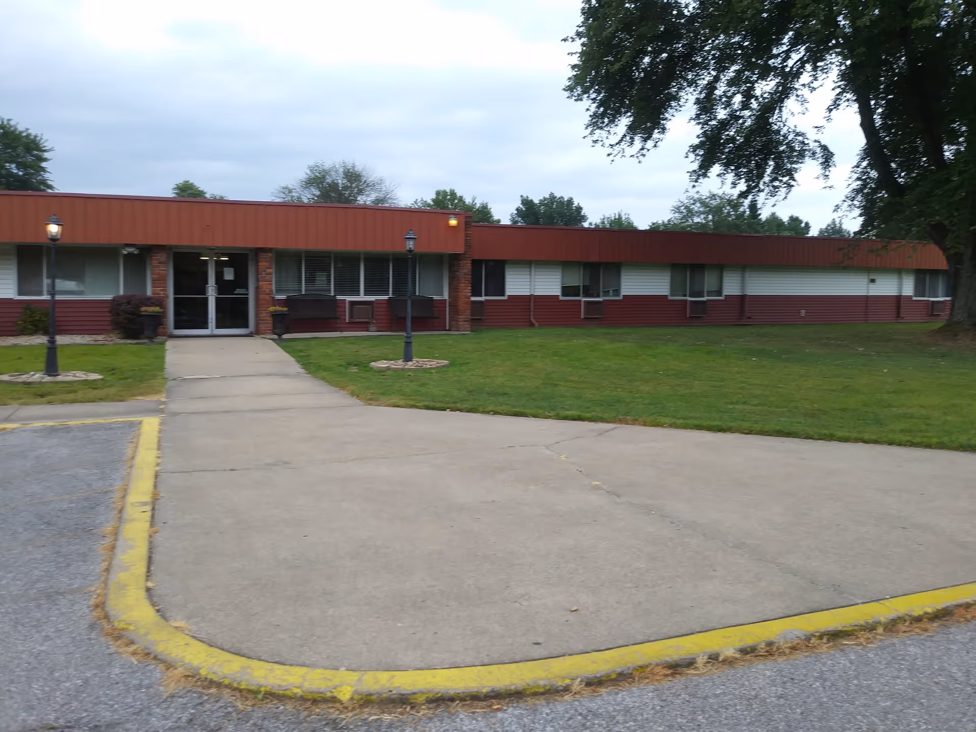 Exterior view of a low, single-story senior facility with a front entrance and lawn.