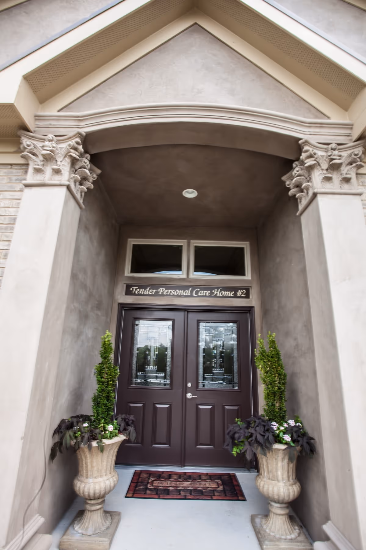 Front entrance of Tender Personal Care Home #2 with decorative columns and potted plants.
