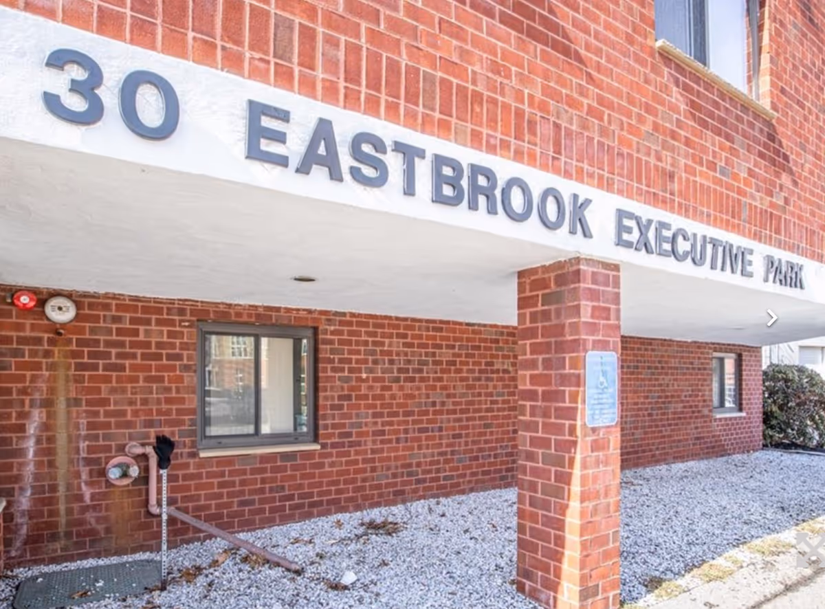 Exterior brick facade of a facility with a sign reading 30 Eastbrook Executive Park.