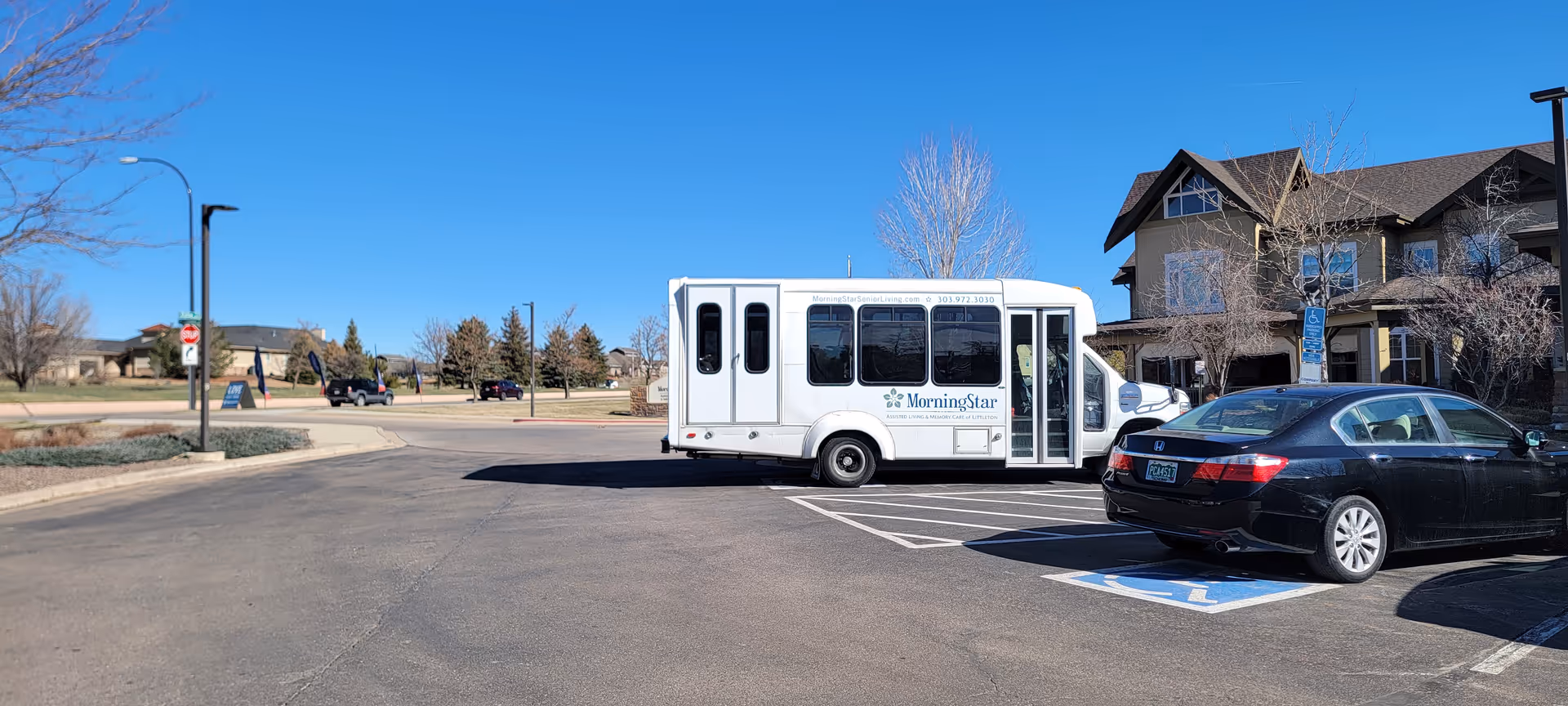 A white MorningStar shuttle bus parked in a lot beside a large facility building.