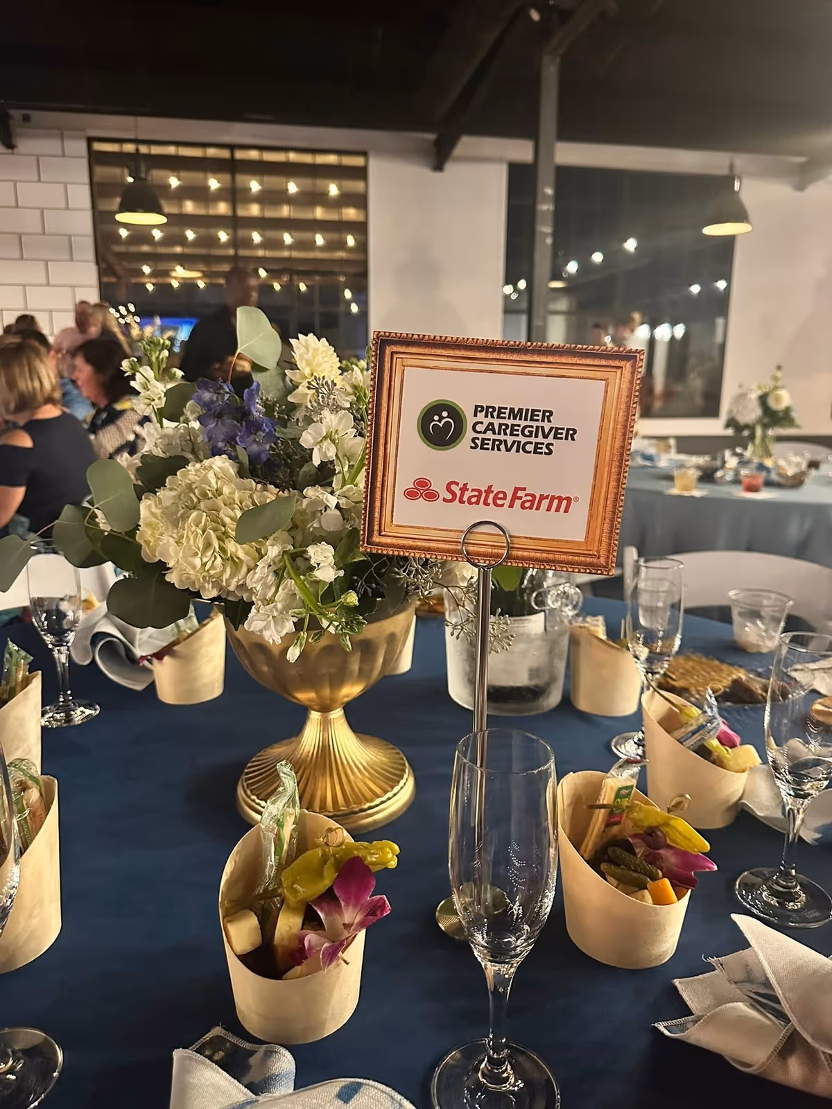Elegant dining table setup with floral centerpiece and sign reading Premier Caregiver Services.