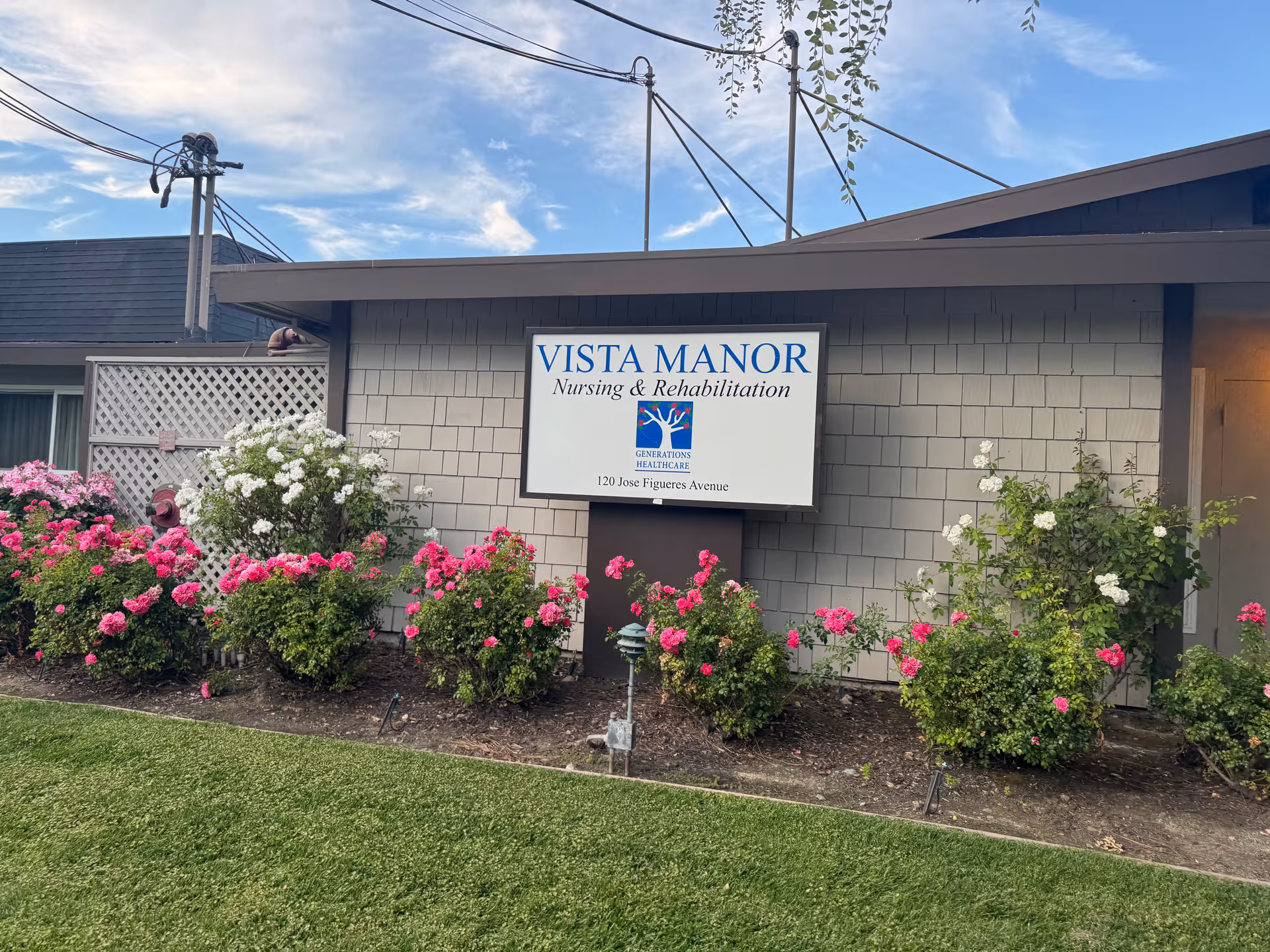 Vista Manor Nursing & Rehabilitation sign on a gray building with rose bushes in front