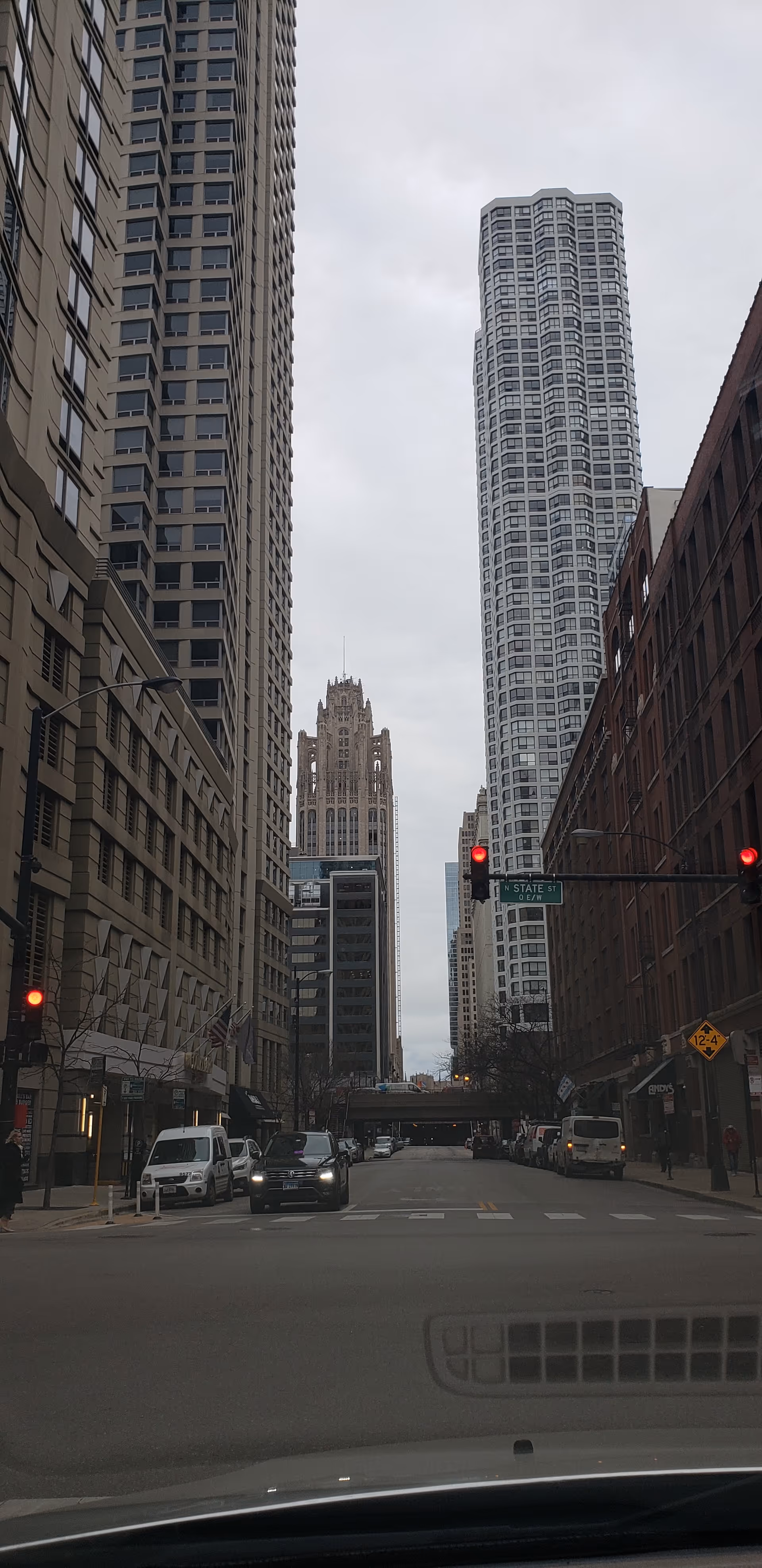 Urban street view with tall buildings on both sides and vehicles.