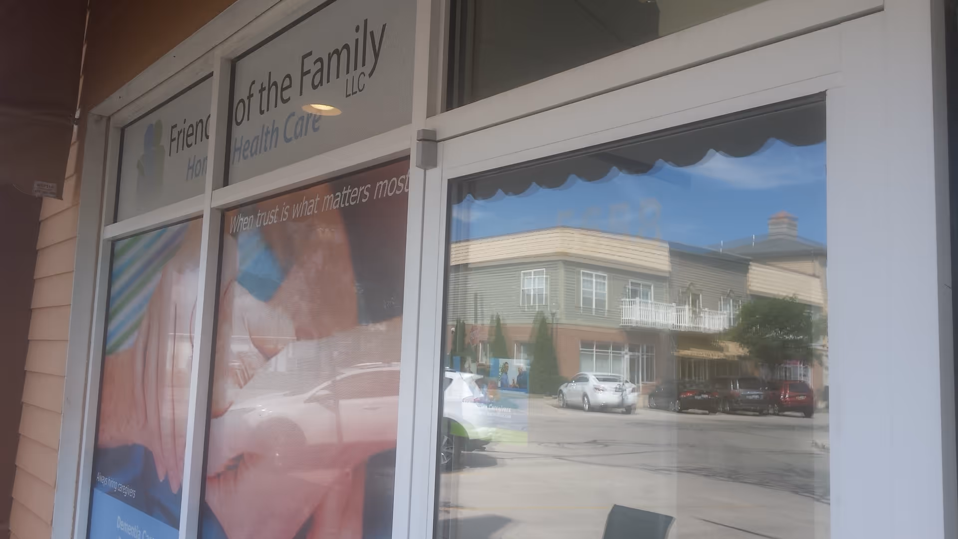 Storefront window displays Friends of the Family Home Health Care sign with street reflection.