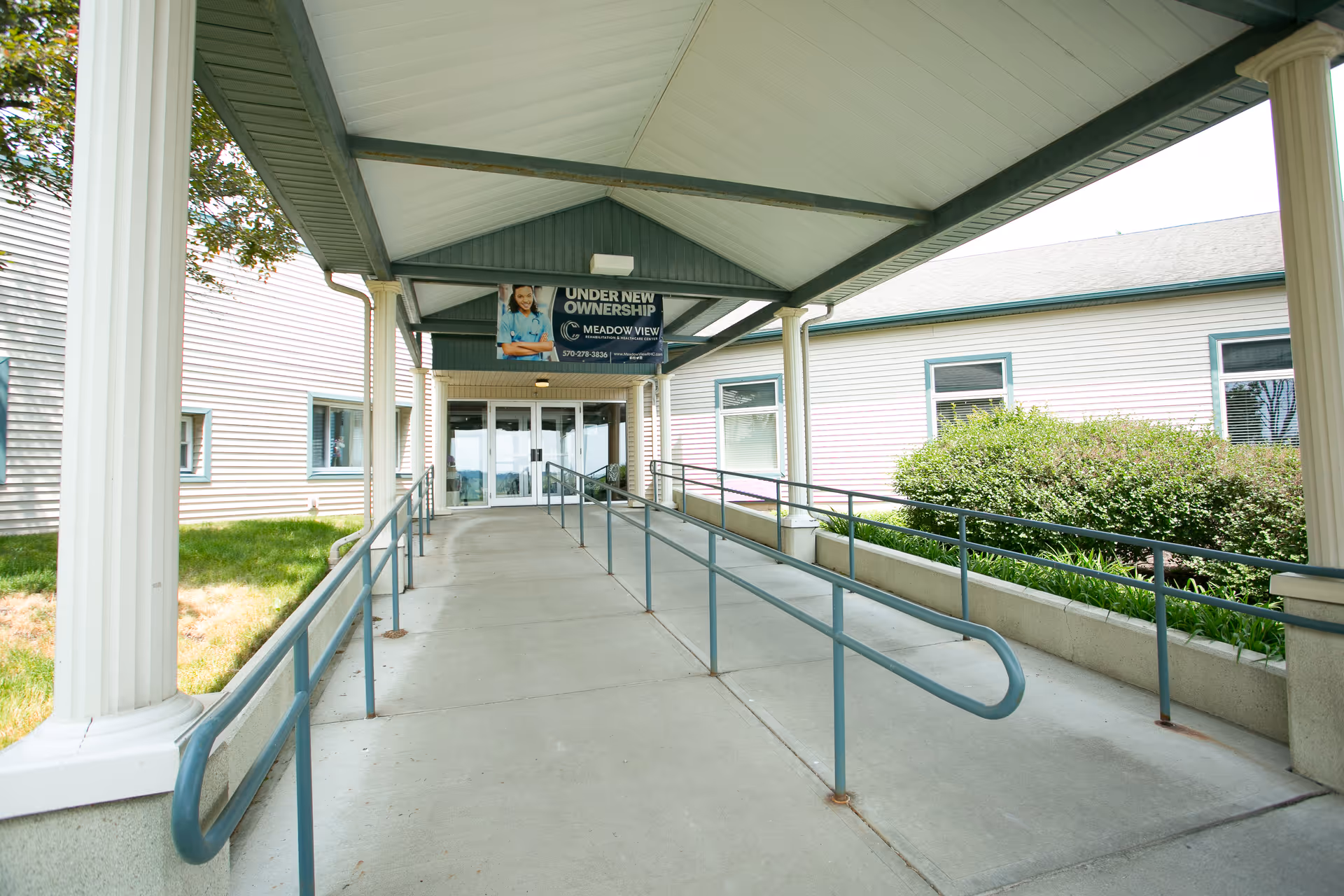 Covered entrance ramp with handrails leading to the front doors of Meadow View Rehabilitation and Healthcare Center.
