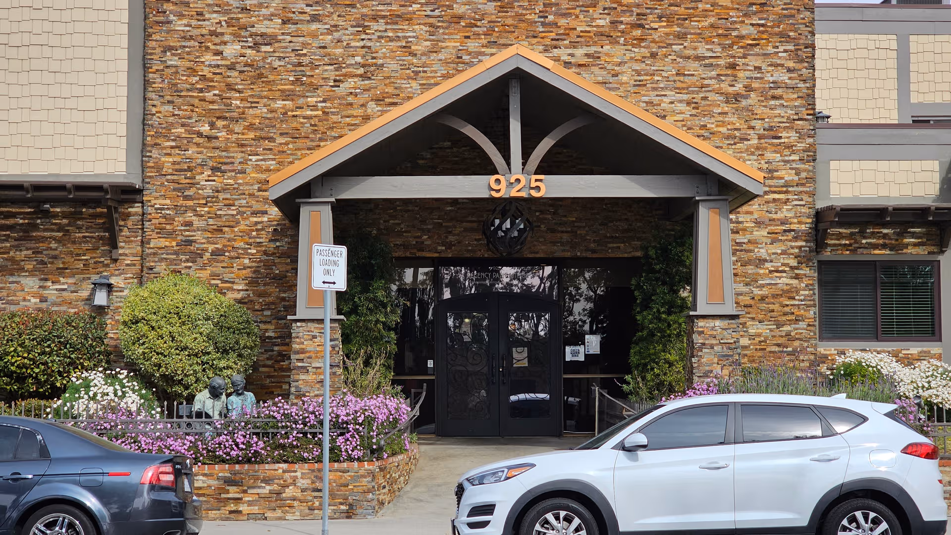 Exterior of Astoria Park Senior Living with stone facade, entrance, and landscaped flower beds.