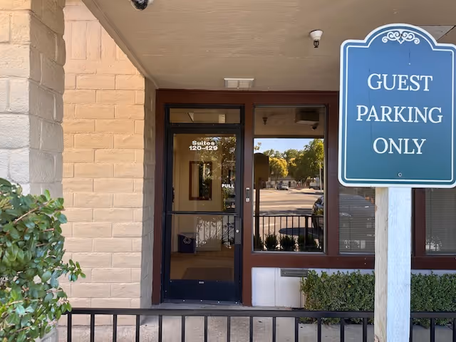 Entryway to a senior living facility with glass door and guest parking sign