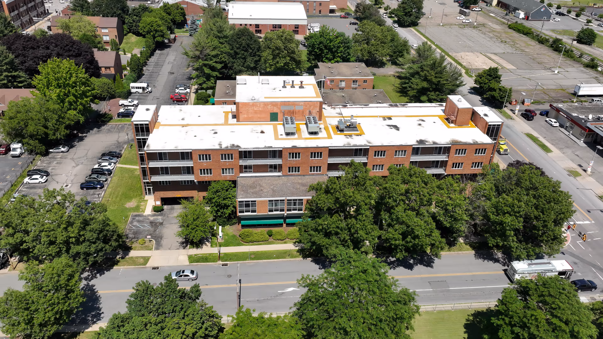 Aerial view of a brick senior living facility surrounded by trees and streets.