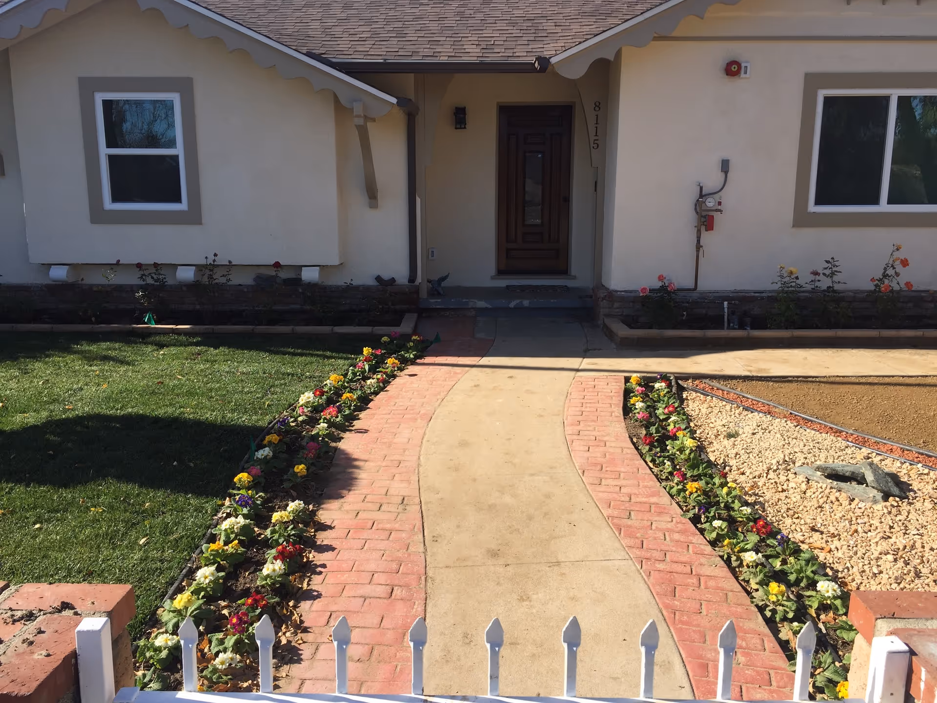 Front entrance of Primrose Senior Care Home with brick walkway, flower borders, and a wooden door.