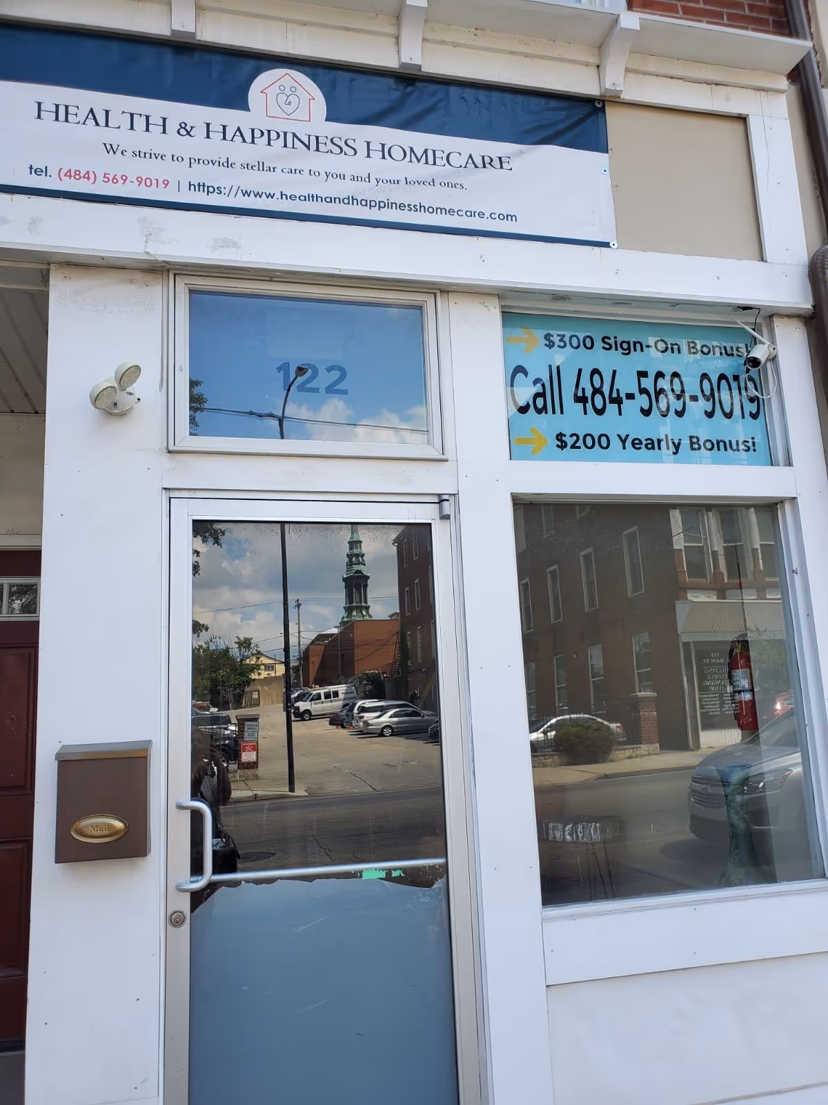 Exterior front of Health & Happiness Homecare with glass door and sign banner.