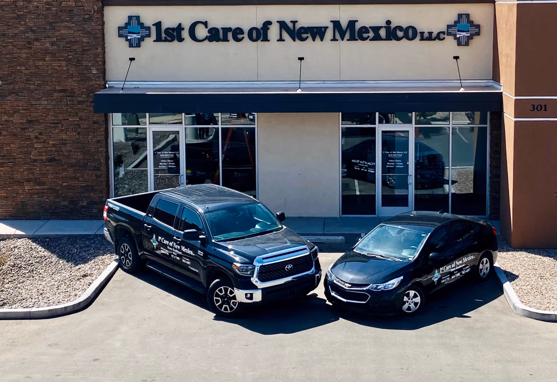 Exterior view of 1st Care of New Mexico LLC building with two company vehicles parked.