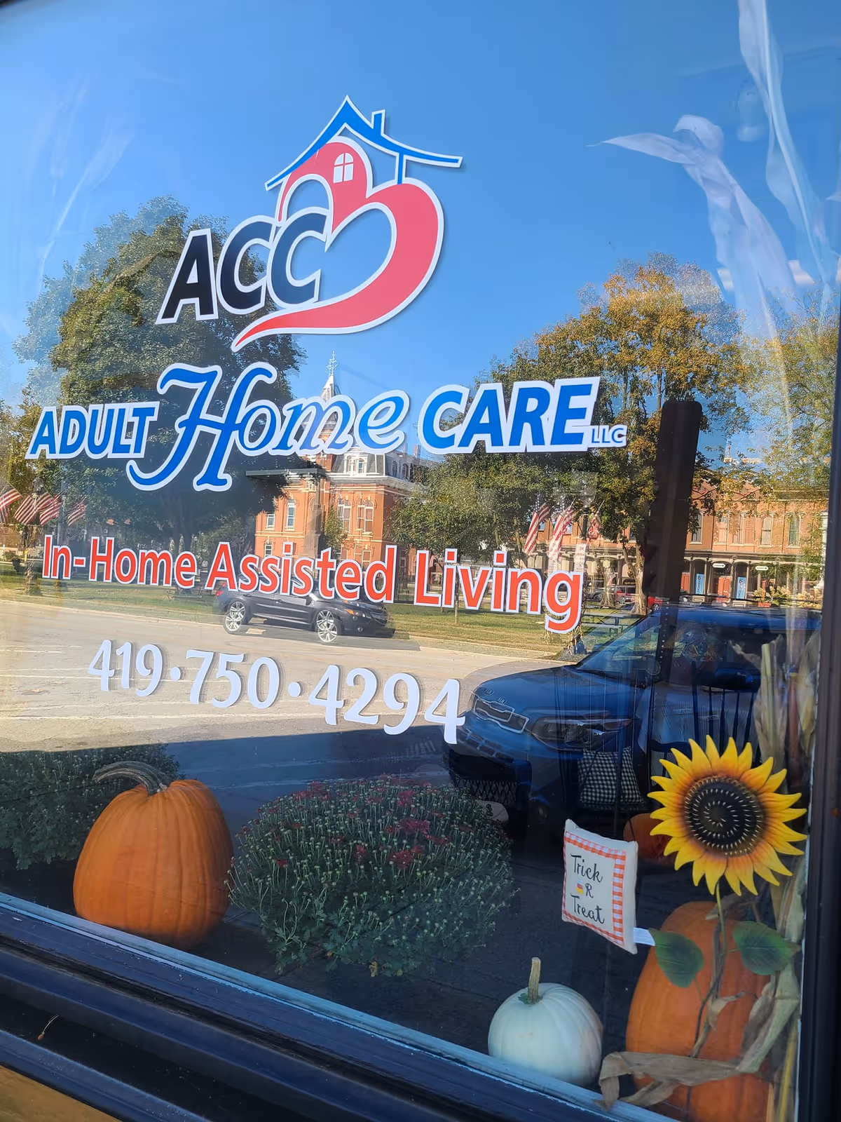 Storefront window for ACC Adult Home Care of Milan, Ohio, with autumn pumpkins.