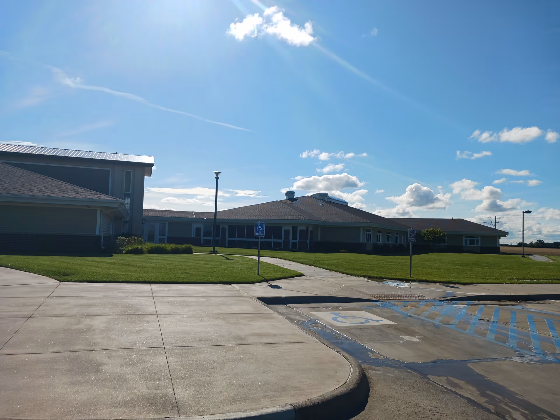 Front exterior view of a single-story senior facility with manicured lawn and parking.