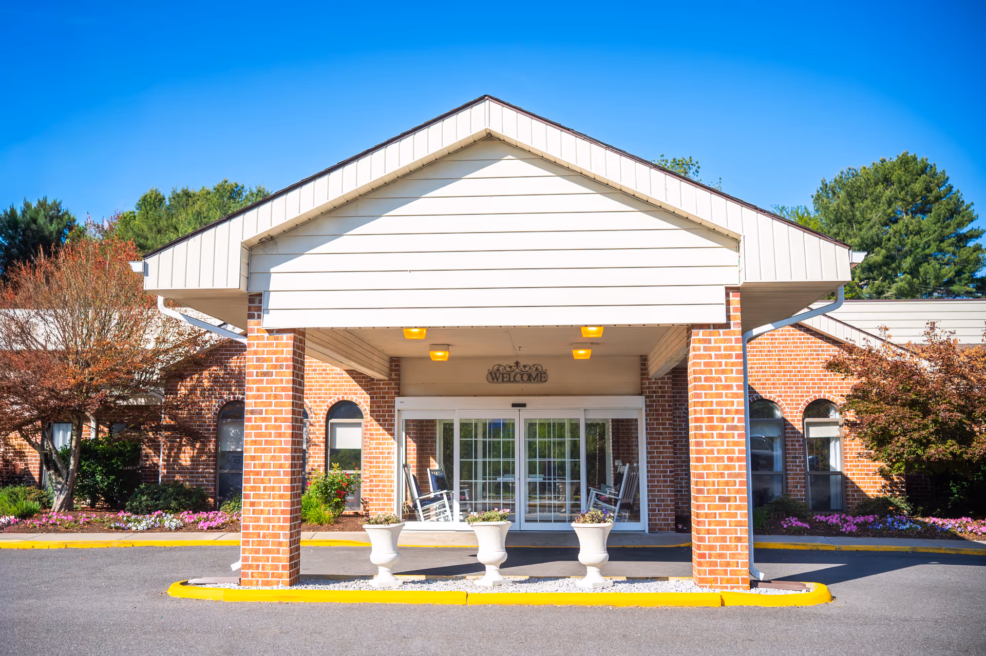 Front entrance of Commonwealth Senior Living at Hillsville with brick exterior and rocking chairs.