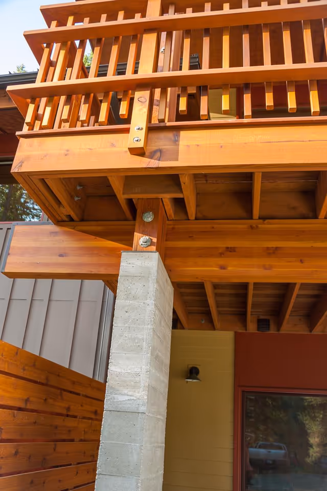 Exterior view of a wooden deck with railing and concrete support pillar.