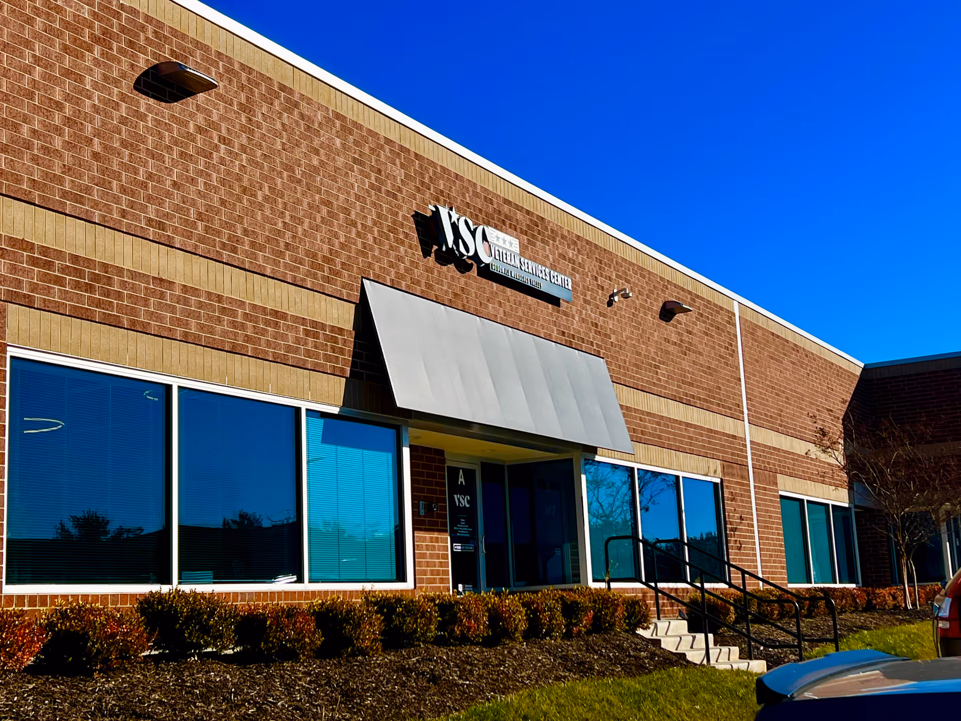 Brick exterior of a Thrive USA Home Care facility with large windows and entrance stairs.